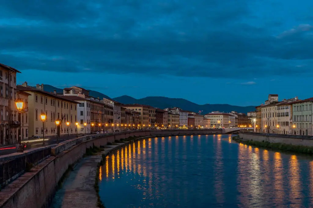 Lanterns from Pisa’s Luminara glowing on the Arno at night.
