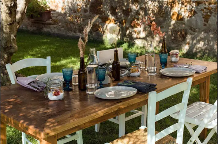 Elegant alfresco dining in the Tuscan countryside with gourmet dishes, wine, and panoramic vineyard views at sunset.